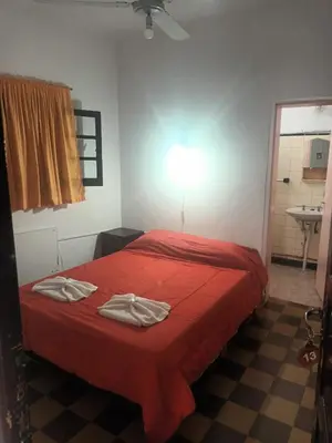 a bedroom with a red bed and a sink at Hotel Agüero in Mina Clavero