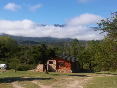 a small cabin in a field with mountains in the background at Apart & Cabañas 
