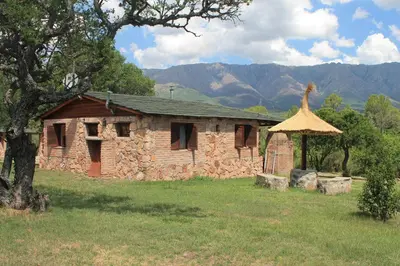 an old stone house with a roof on a field at Apart & Cabañas 