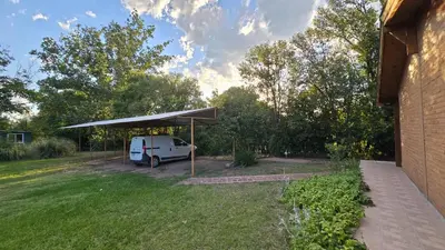 a white van parked under a canopy in a yard at Hosteria Rural Piedra y Camino in Nono