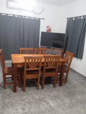 a wooden dining table and chairs with a television at Piquillin San Lorenzo in San Lorenzo