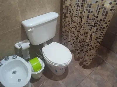 a bathroom with a white toilet and a shower curtain at Piquillin San Lorenzo in San Lorenzo