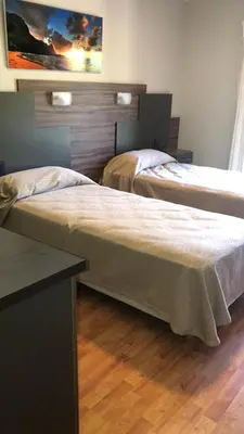 two beds in a room with wooden floors at Hotel Rincon Del Este in General Deheza