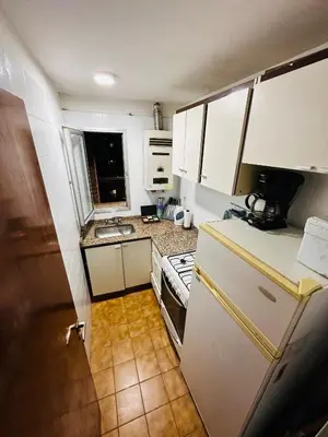 a small kitchen with white cabinets and a refrigerator at Refugio Urbano in Cordoba