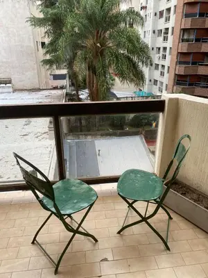 two green chairs on a balcony with a palm tree at Departamento -Balcarce- Nueva Córdoba, ByApartcba in Cordoba