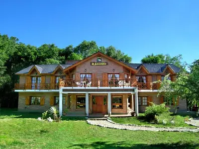 a large wooden house with a large porch at Posada La Escondida in Villa General Belgrano