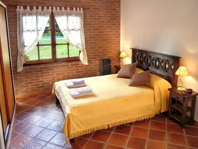 a bedroom with a large bed with a brick wall at Posada La Escondida in Villa General Belgrano