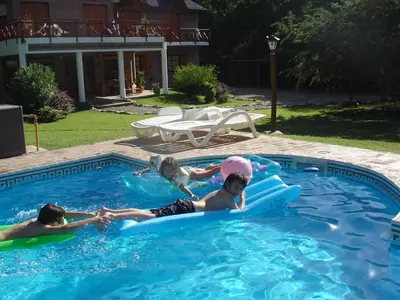 three children are playing in a swimming pool at Posada La Escondida in Villa General Belgrano
