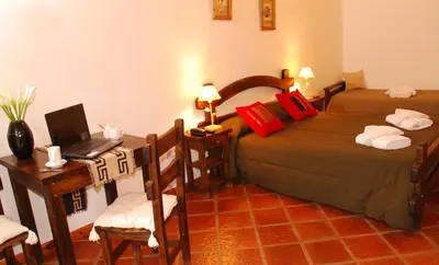 a bedroom with two beds and a desk with a laptop at Posada La Escondida in Villa General Belgrano