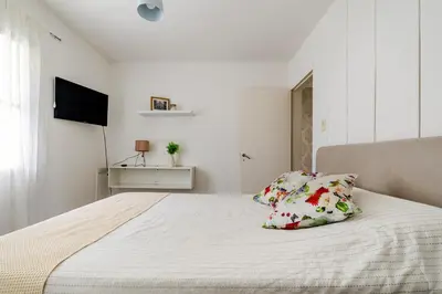 a white bedroom with a bed and a television at Familia y Amigos con Pileta, Asador y Cochera in Cordoba