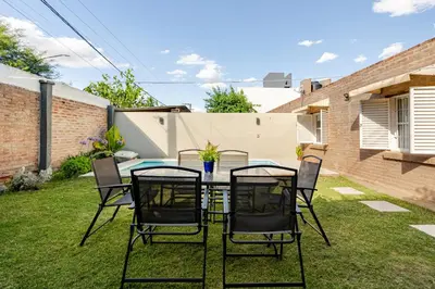 a patio with a table and chairs on the grass at Familia y Amigos con Pileta, Asador y Cochera in Cordoba