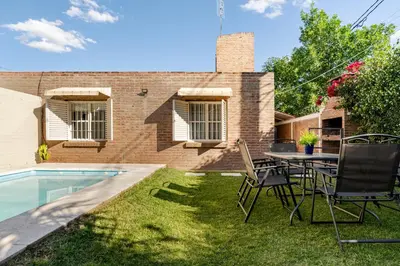 a backyard with a table and chairs next to a house at Familia y Amigos con Pileta, Asador y Cochera in Cordoba