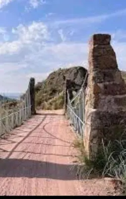 a bridge over a dirt road with a fence at Mis Aromos in Mina Clavero