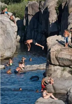 a group of people jumping into a pool of water at Mis Aromos in Mina Clavero
