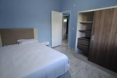 a bedroom with a white bed and a wooden cabinet at Cabaña dpto en Villa de Merlo in Merlo