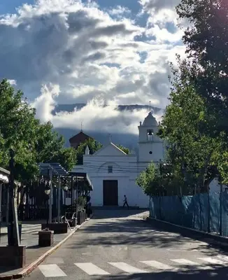 a white building with a clock tower on a street at Cabaña dpto en Villa de Merlo in Merlo