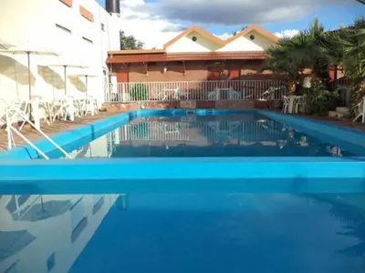 a blue swimming pool in front of a house at Hotel Car Mar in Mina Clavero