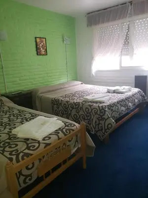 two beds in a room with green walls at Hotel Car Mar in Mina Clavero