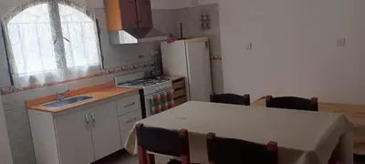 a kitchen with a table and a white refrigerator at Mis helechos in Mina Clavero