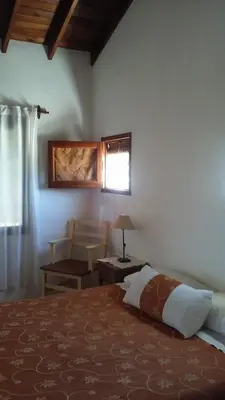 a bedroom with a bed and a table and a window at La Soleada in Mina Clavero