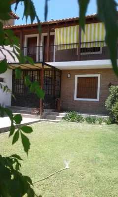 a house with a balcony on top of a yard at La Soleada in Mina Clavero