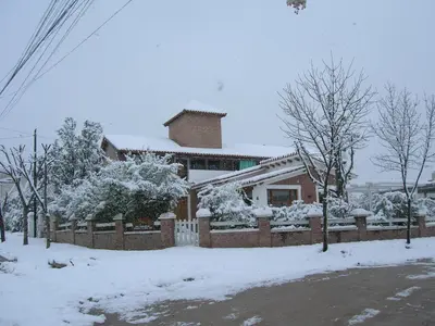 a house with a fence covered in snow at La Soleada in Mina Clavero