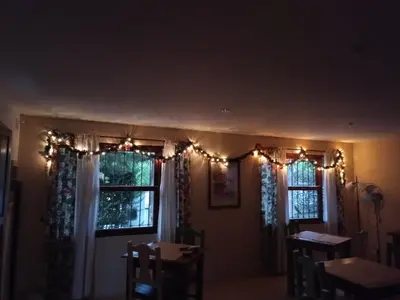 a dining room with christmas lights and two windows at La Soleada in Mina Clavero