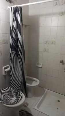 a bathroom with a toilet with a black and white shower curtain at CASA AMPLIA Y CONFORTABLE in Cordoba