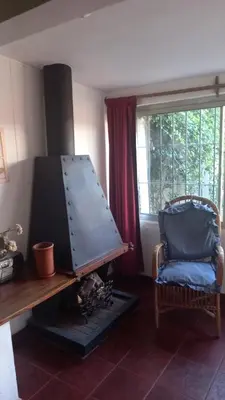 a living room with a fireplace with a chair and a table at CASA AMPLIA Y CONFORTABLE in Cordoba