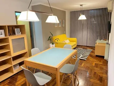 a living room with a dining room table and a yellow couch at Palacio 210 - Plaza España - Nueva Córdoba - 2 dormitorios in Cordoba