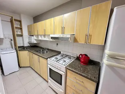 a kitchen with wooden cabinets and a white stove top oven at Palacio 210 - Plaza España - Nueva Córdoba - 2 dormitorios in Cordoba