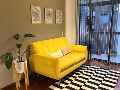 a yellow couch in a living room with a plant at Palacio 210 - Plaza España - Nueva Córdoba - 2 dormitorios in Cordoba