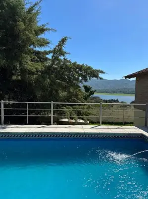 a large blue swimming pool next to a fence at Casa vista panorámica al lago in Cordoba