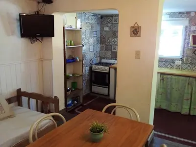 a room with a table and a kitchen with a stove at Alojamiento frente al Arroyo Cristal in Tanti