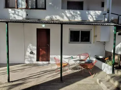 a patio with a table and chairs and a door at Alojamiento frente al Arroyo Cristal in Tanti
