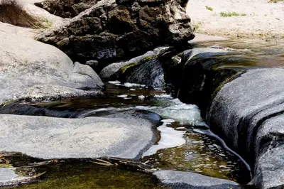 a stream of water with rocks in the middle at Alojamiento frente al Arroyo Cristal in Tanti