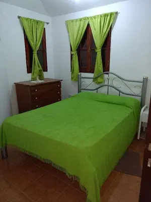 a bedroom with a green bed with a green bedspread at Tu lugar en Tierra Santa in Villa Cura Brochero