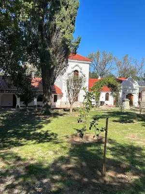 a large white house with a tree in the yard at La Posta del Jesuita in Villa Los Aromos