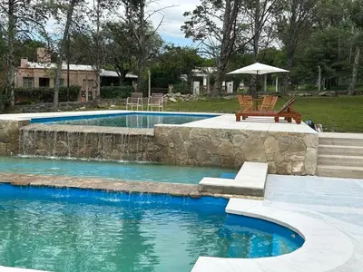 a swimming pool with a bench and an umbrella at La Posta del Jesuita in Villa Los Aromos
