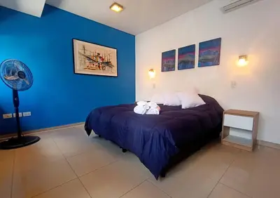 a bedroom with a bed with blue walls and a fan at Cómodo Depto en B Villa Belgrano in Cordoba