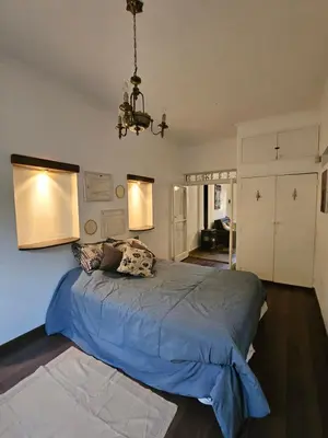 a bedroom with a large bed with blue sheets and a chandelier at Martinolli5130 in Cordoba