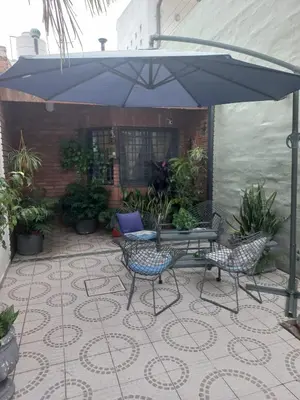 a patio with a table and chairs under an umbrella at Departamento interno con dos camas individuales in Cordoba