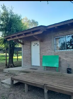 a house with a green bench in front of it at Cabaña Serrana in Santa Rosa de Calamuchita
