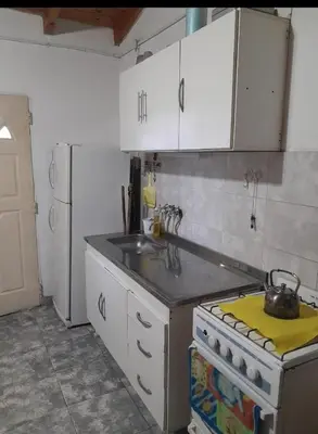 a kitchen with white cabinets and a stove and a sink at Cabaña Serrana in Santa Rosa de Calamuchita