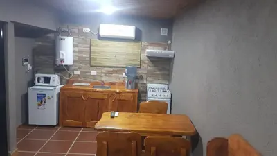 a small kitchen with a wooden table and a refrigerator at Alojamiento Tanti in Villa Santa Cruz del Lago