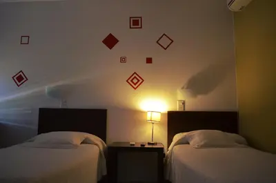 a hotel room with two beds and a clock on the wall at Hotel La Posada del Viajero in Río Cuarto