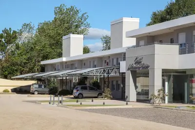 a white building with cars parked in front of it at Hotel La Posada del Viajero in Río Cuarto