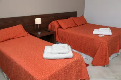 two beds in a room with two white towels at Hotel La Posada del Viajero in Río Cuarto