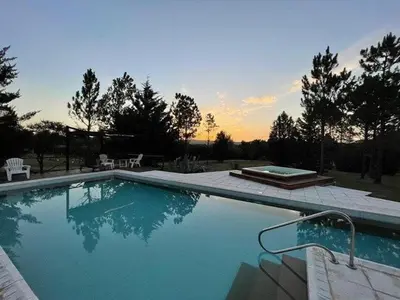 a large swimming pool with a sunset in the background at Cortaderas Hotel de Campo Nono in Nono