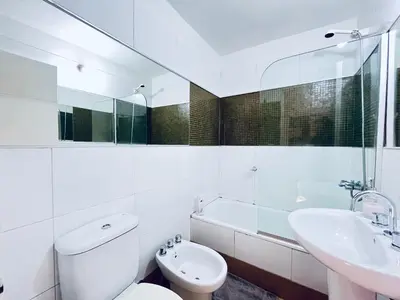 a white bathroom with a toilet and a sink at Departamento Chacabuco in Cordoba